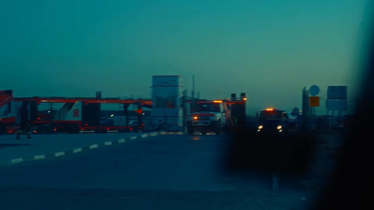 Camions de dépannage et véhicules avec feux de signalisation sur une route au lever du jour, scène de récupération de voiture.