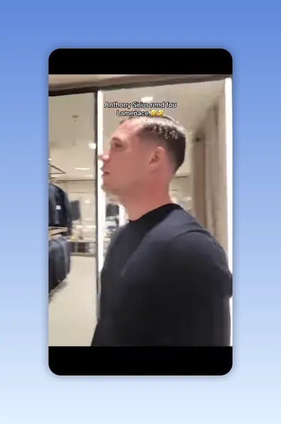 Intérieur de boutique avec miroir, portants de vêtements et homme en pull noir de profil