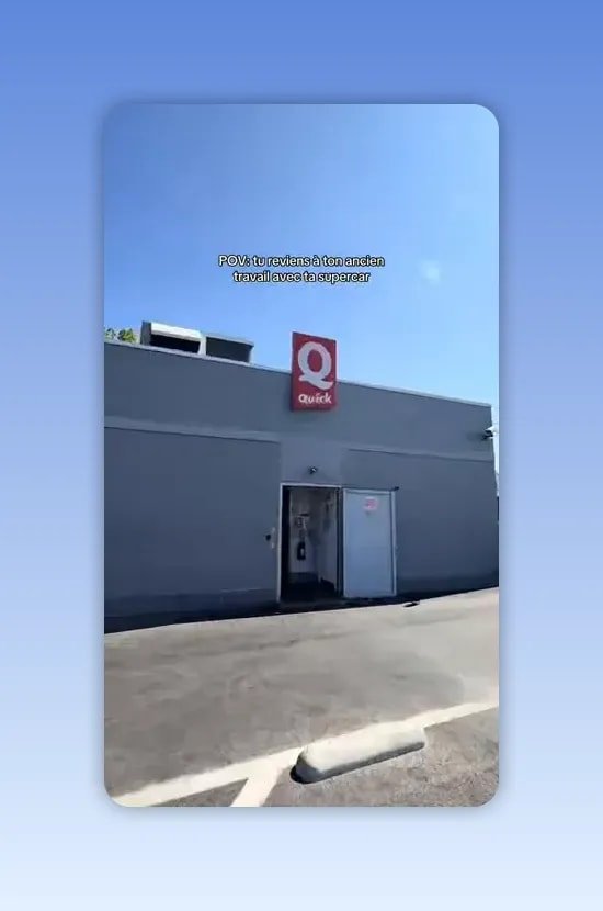 Bâtiment gris avec le logo Quick rouge au-dessus d'une porte ouverte sous un ciel bleu
