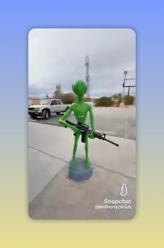 Statue verte d extraterrestre mince tenant un grand objet noir dans un parking